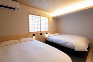 A hotel room with two beds, a window with a grid pattern, and an air conditioning unit. - Beppu Yunagi (Noguchi Nakamachi, Beppu Shi)