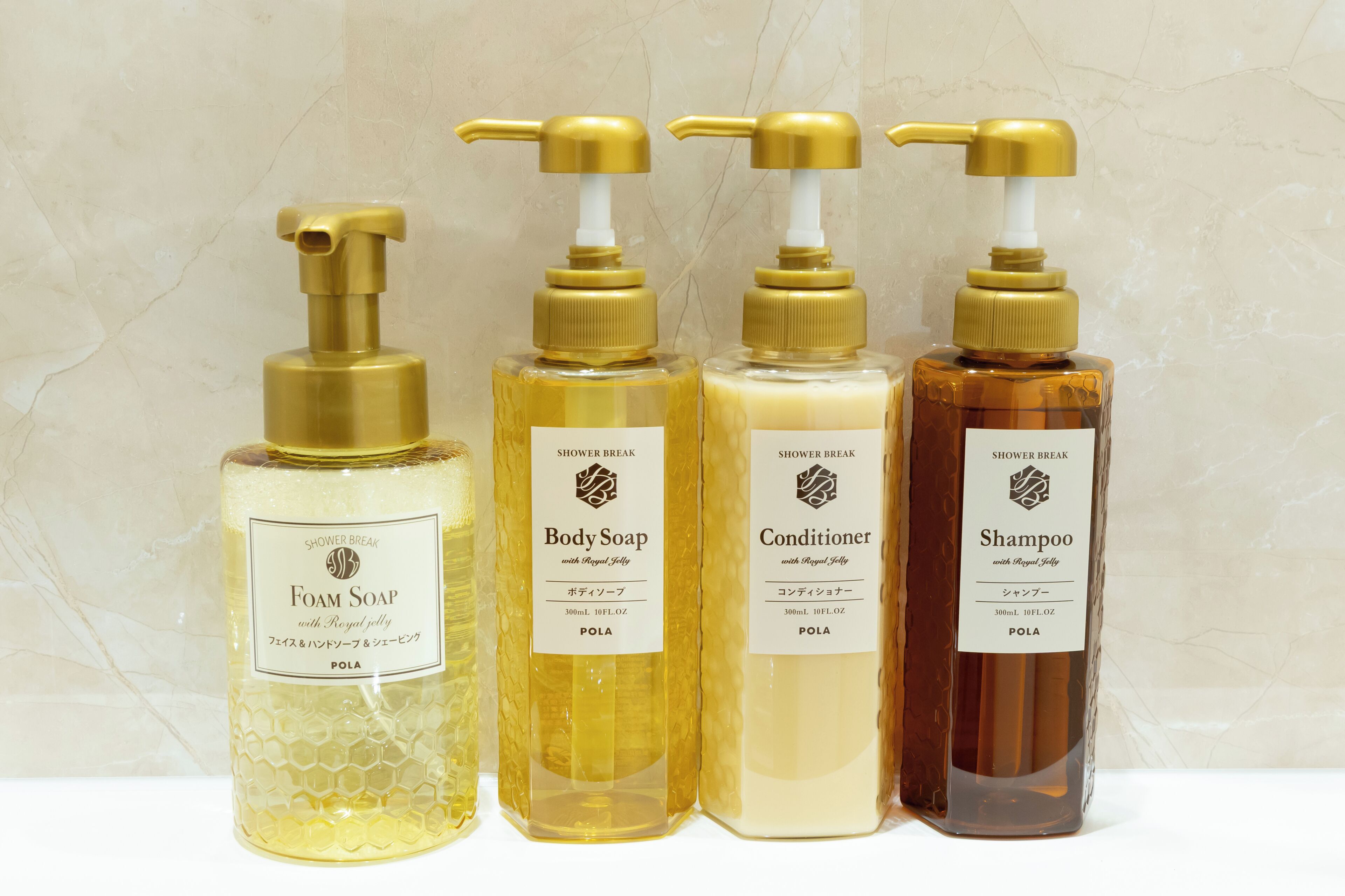 Four bottles of shower break products with pumps, each labeled with the brand name and product type.