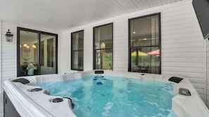 Ein Whirlpool mit Blick auf ein Haus und eine draußen sitzende Person.
