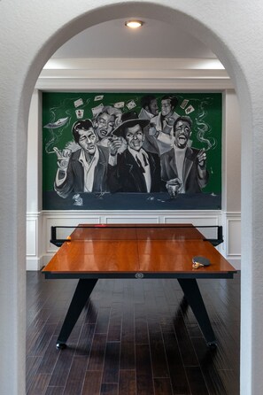 Una mesa de billar en una habitación con un mural de pared verde.