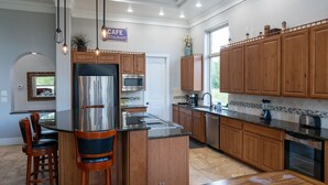 A modern kitchen with a central island, wooden cabinets, stainless steel appliances, and pendant lighting.
