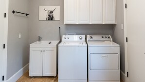 A laundry room with a washing machine, dryer, and cabinets.