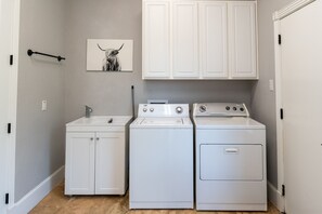 A laundry room with a washing machine, dryer, and cabinets.