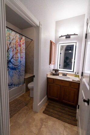 A bathroom with a shower curtain, a sink, a mirror, and a toilet.
