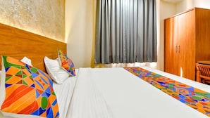 A hotel room with a bed, a wooden wardrobe, a window with curtains, and a colorful geometric-patterned runner. - Hotel KPL (Jaipur)