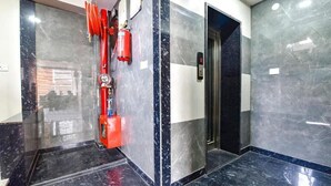 A modern elevator with a digital display, a fire extinguisher, and a red hose on the wall. - Hotel KPL (Jaipur)