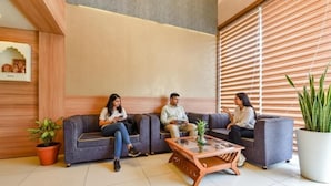 A modern lobby with three sofas, a glass coffee table, and potted plants. - Hotel KPL (Jaipur)