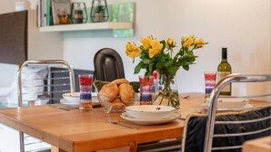 A dining table with a vase of yellow flowers, a bowl of bread, and a glass of red drink. - Stylish vacation apartment with terrace (Westendorf)