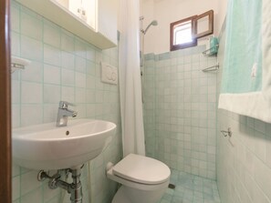 Un baño con lavamanos, inodoro, ducha y paredes de azulejos.
