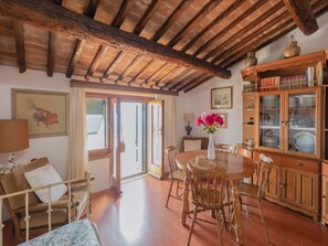 A rustic dining area with wooden furniture, a tiled floor, and a traditional wooden cabinet with glass doors. - Charming house with a Stunning Panoramic Terrace (Marciana)
