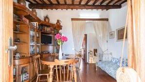 Habitació rústica amb taula de dinar de fusta, cadires, una prestatgeria i un llit amb dosser.