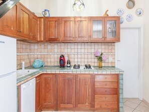 A kitchen with wooden cabinets, a tiled backsplash, a coffee maker, a bottle of champagne, and a vase with flowers. - Charming house with a Stunning Panoramic Terrace (Marciana)