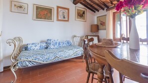 Una habitació amb un llit, una taula de dinar amb caires, una làmpada i quadres a les parets.