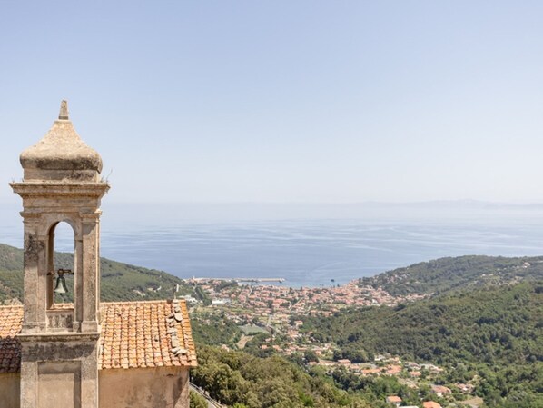 Una torre de campanas con tejado de baldosas que domina un pueblo costero.
