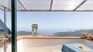 Un balcó amb una taula, cadires i vista a una torre i un paisatge.