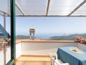 Ein Balkon mit Tisch, Stühlen und Blick auf einen Turm und die Landschaft.