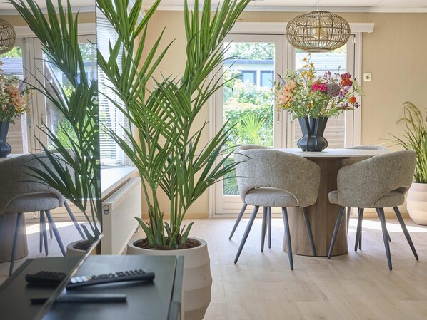 A dining area with a table, chairs, a potted plant, and a hanging light fixture.