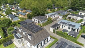 A residential area with modern houses, solar panels, and a well-maintained lawn.