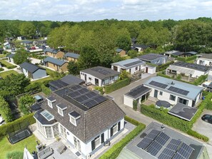 A residential area with modern houses, solar panels, and a well-maintained lawn.