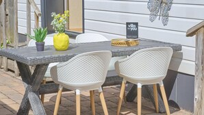 A patio with wicker furniture, a yellow vase with flowers, and a sign reading 'villa for you'.