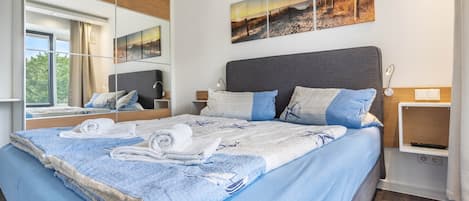 A modern bedroom with a large bed, a mirror, and artwork on the wall.