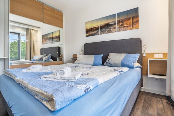 A modern bedroom with a large bed, a mirror, and artwork on the wall.