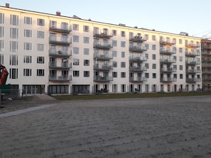 En flereetagers boligbygning med altaner, et fladt tag og en byggekran forgrunden.