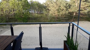 En balkon med udsigt over en sandstrand og frodig vegetation.