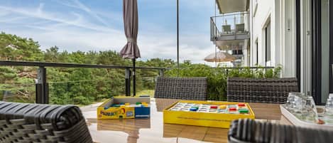 Un balcon avec une table, des chaises et une boîte de jouets pour enfants.