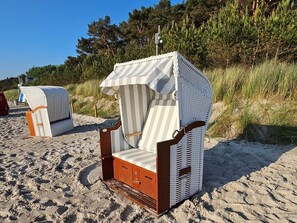 En strandstol med markise med striber, et træstel og en metalramme.