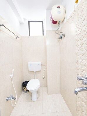 A small, modern bathroom with a toilet, shower, and a toilet paper holder. - Hotel Corbett Fun Resort  (Ramnagar)