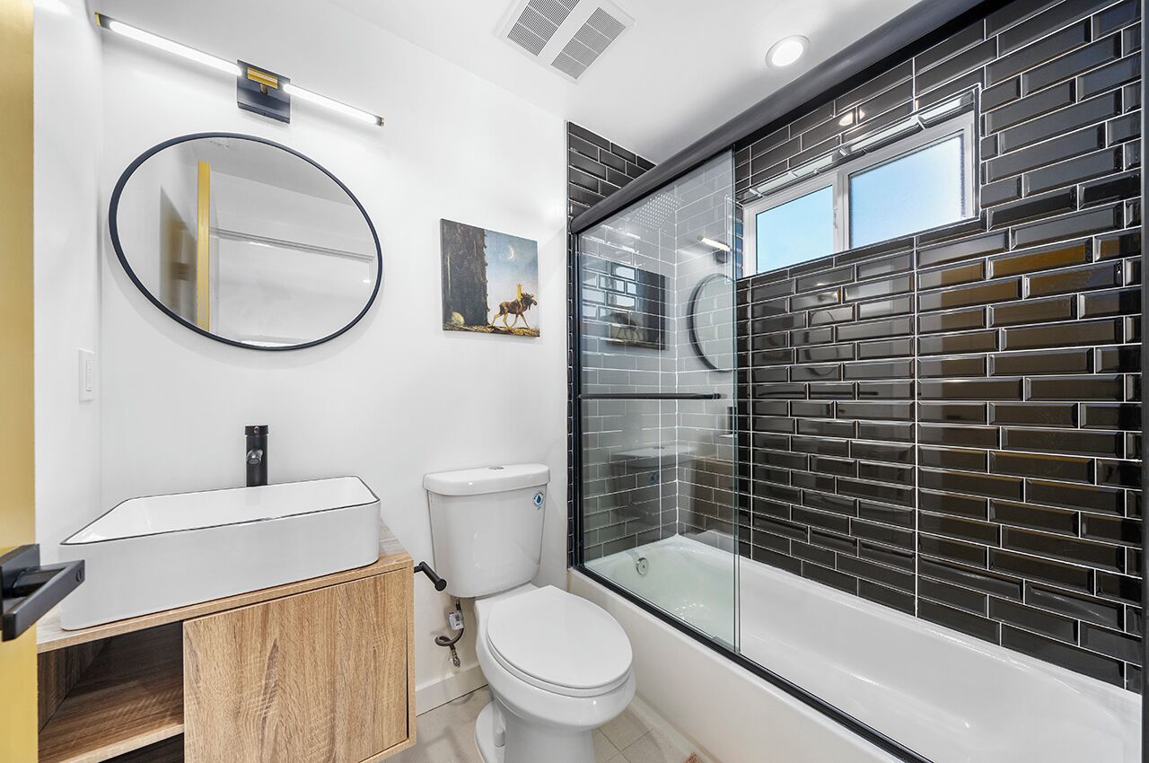Un baño moderno con lavamanos, inodoro y bañera blancos.