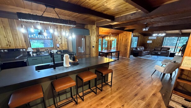 Interior de una cabaña de madera con cocina, barra y zona de estar.
