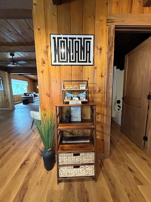 A wooden interior with a sign reading 'Montana' and a shelf with various items including a plant and decorative pieces. - 3-bedroom Cabin in Seeley Lake MT (Seeley Lake)