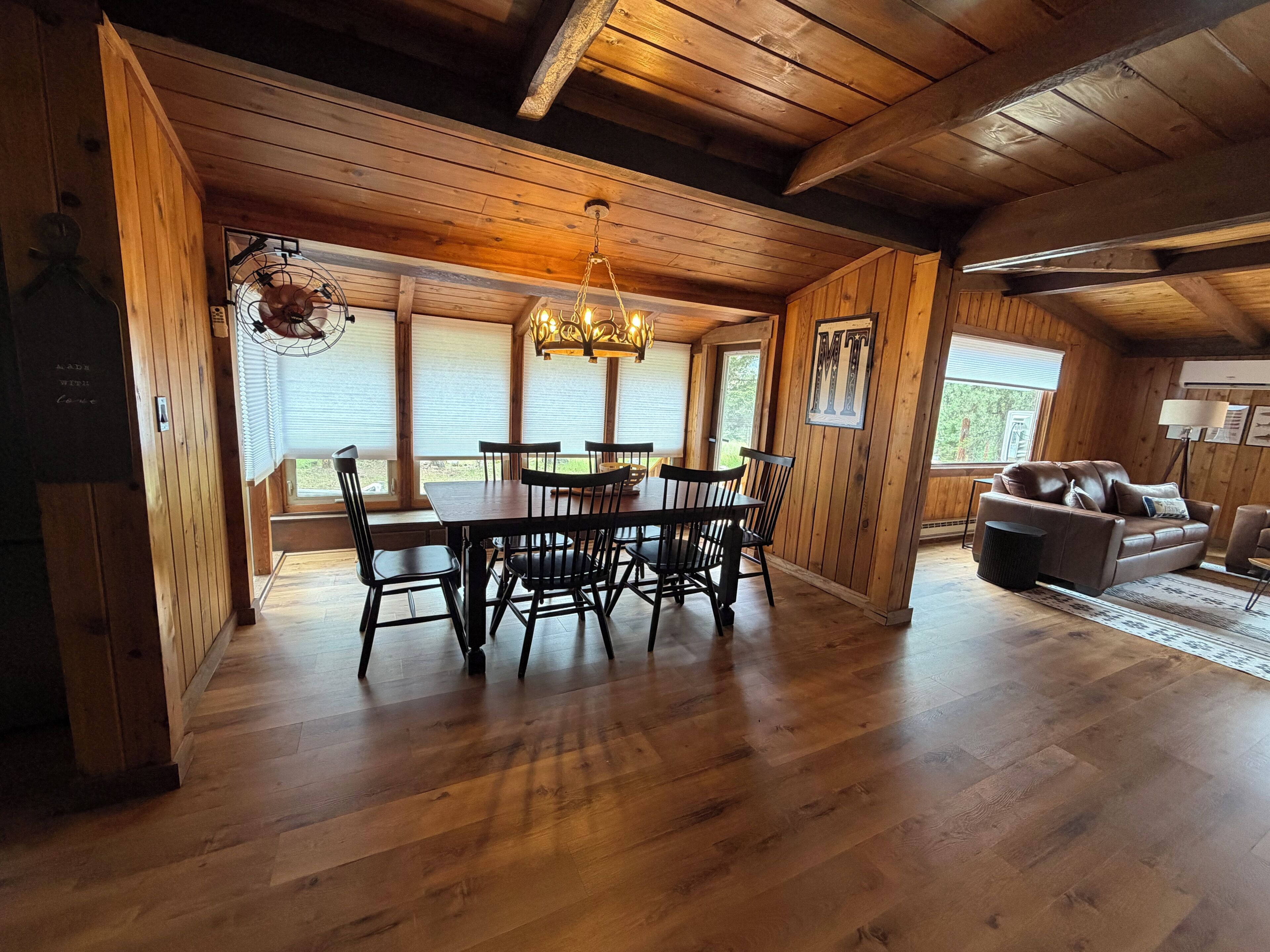A wooden interior with a dining area, a sofa, and a chandelier.