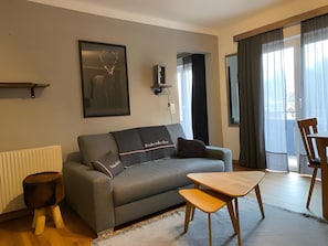 Ein modernes Wohnzimmer mit einem grauen Sofa, einem kleinen Holztisch und einer Heizung.