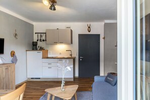 A modern living room with a sofa, a coffee table, and a television. - Apartment 'Kuhglocken' with Mountain View, Shared Garden and Wi-Fi (Döbriach)