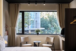 A hotel room with a bed, two chairs, a small table, a TV, and a window with curtains. - Saigon An House (Ho Chi Minh City)
