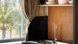 Una cocina con un lavamanos, armarios y una ventana con cortinas.