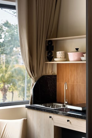 A kitchen with a sink, cabinets, and a window with curtains.