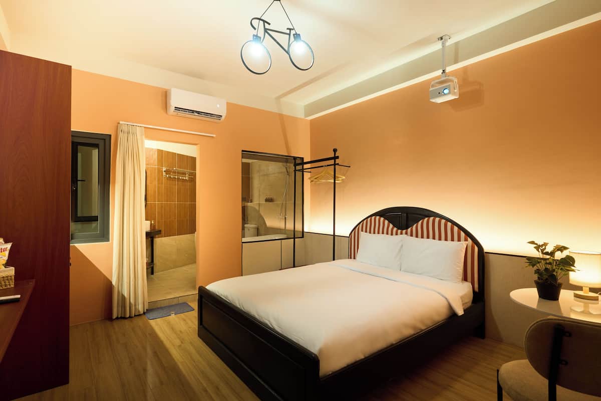 Ein Hotelzimmer mit Bett, Nachttisch, Lampe und einem Deckenprojektor.