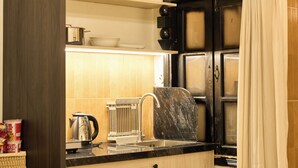 Una cocina compacta con un lavamanos, un hervidor y un cubo de basura.