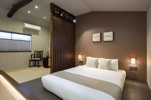 Ein Hotelzimmer mit einem großen Bett, einem Sessel, einer Holzvertäfelung und zwei Wandleuchten.