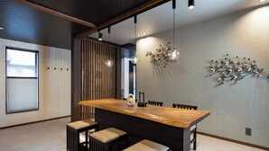 Eine moderne Küche mit einer Holztheke, Barhocker, Pendelleuchten und einem dekorativen Metallkunstwerk an der Wand.