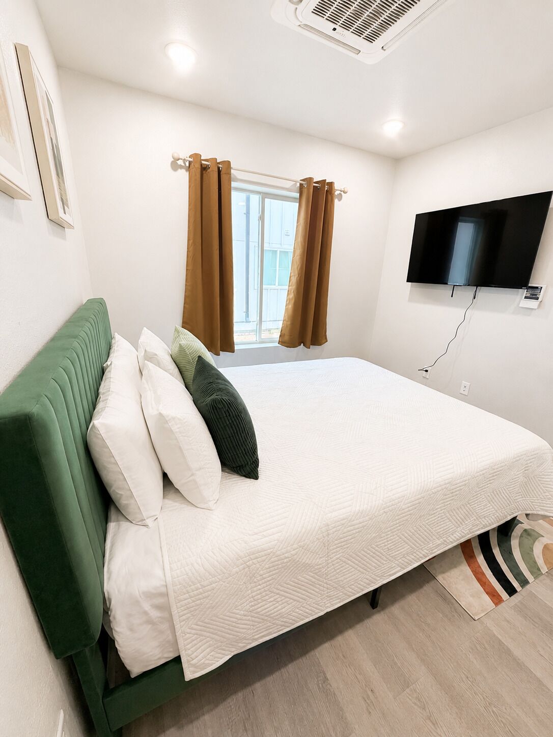 A bedroom with a bed, a television, and a window with curtains.