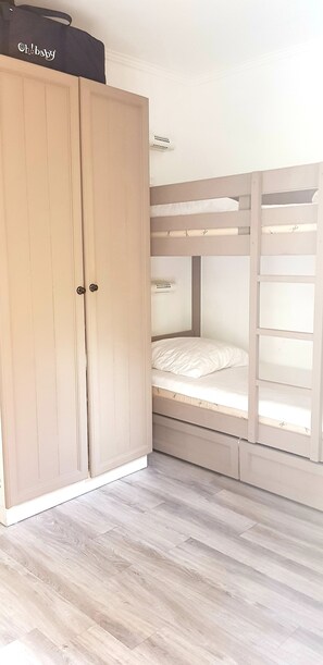 Ein Zimmer mit einem Holzschrank, einem Etagenbett und einem hellen Holzboden.