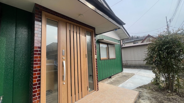 Un immeuble résidentiel à l’extérieur verdoyant, doté d’une porte-fenêtre coulissante et d’une petite fenêtre.