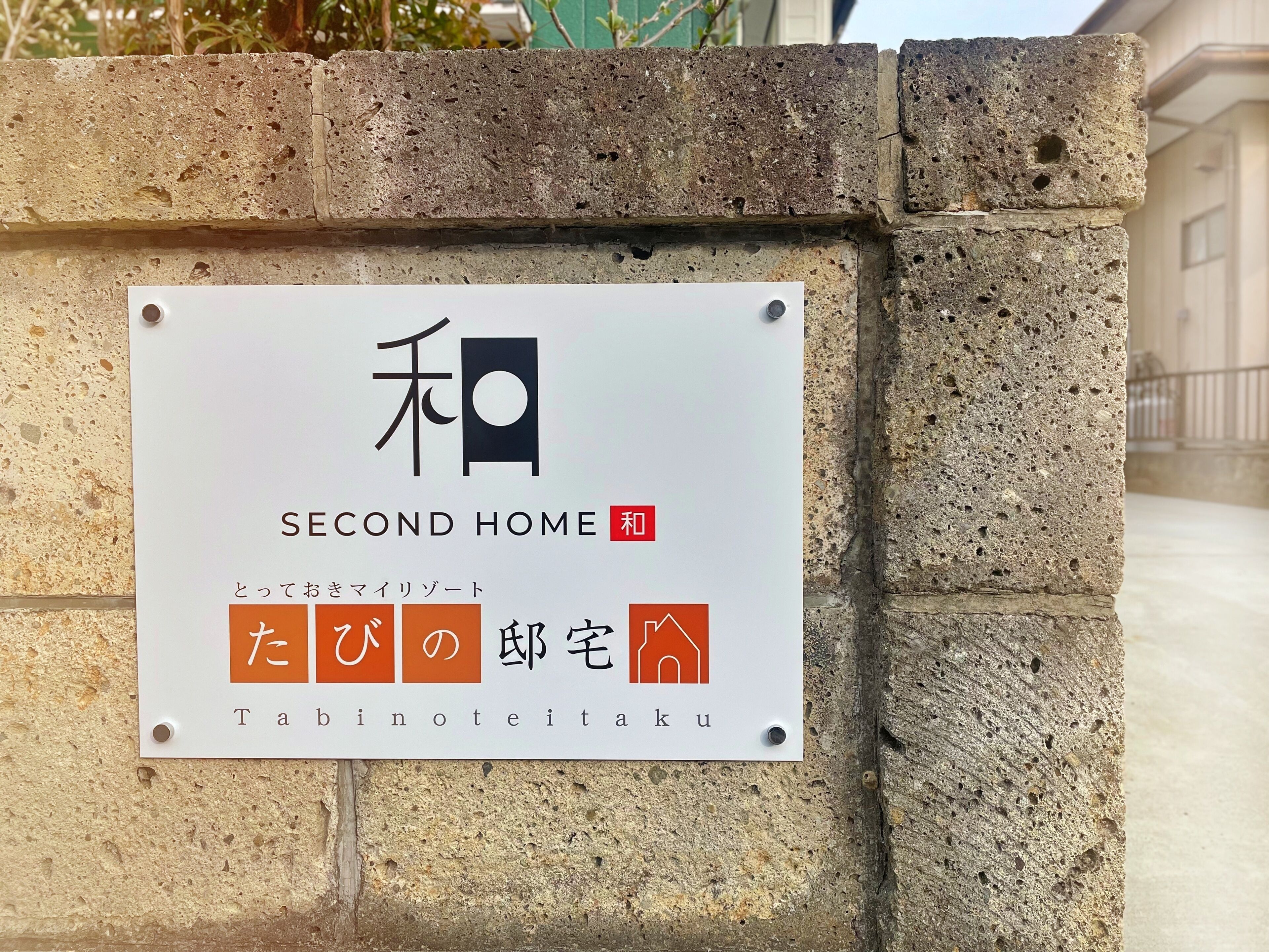 Placa com o nome 'Second Home', texto em japonês e um símbolo indicando área residencial.