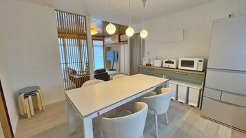 Una cocina moderna con una mesa blanca, sillas y un microondas.