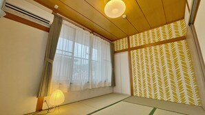 Una habitación japonesa tradicional con suelo de tatami, un mamparo shoji y un ventilador de techo.
